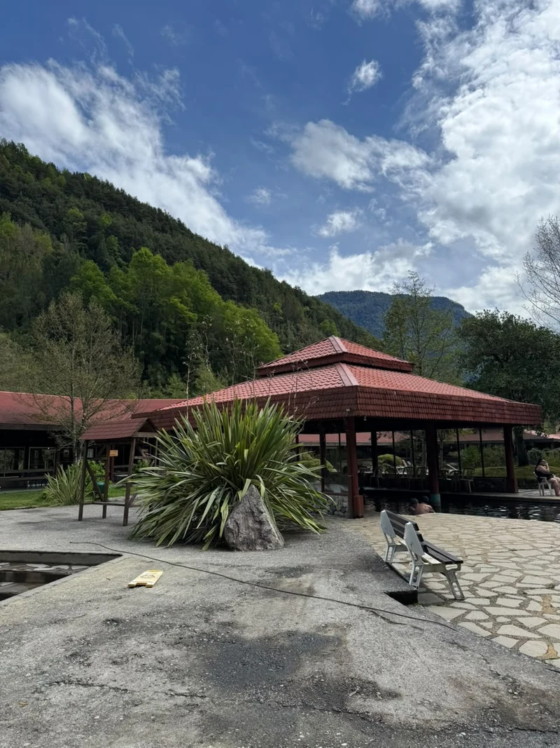 Piscina exterior y construcción de techo rojo frente a los cerros