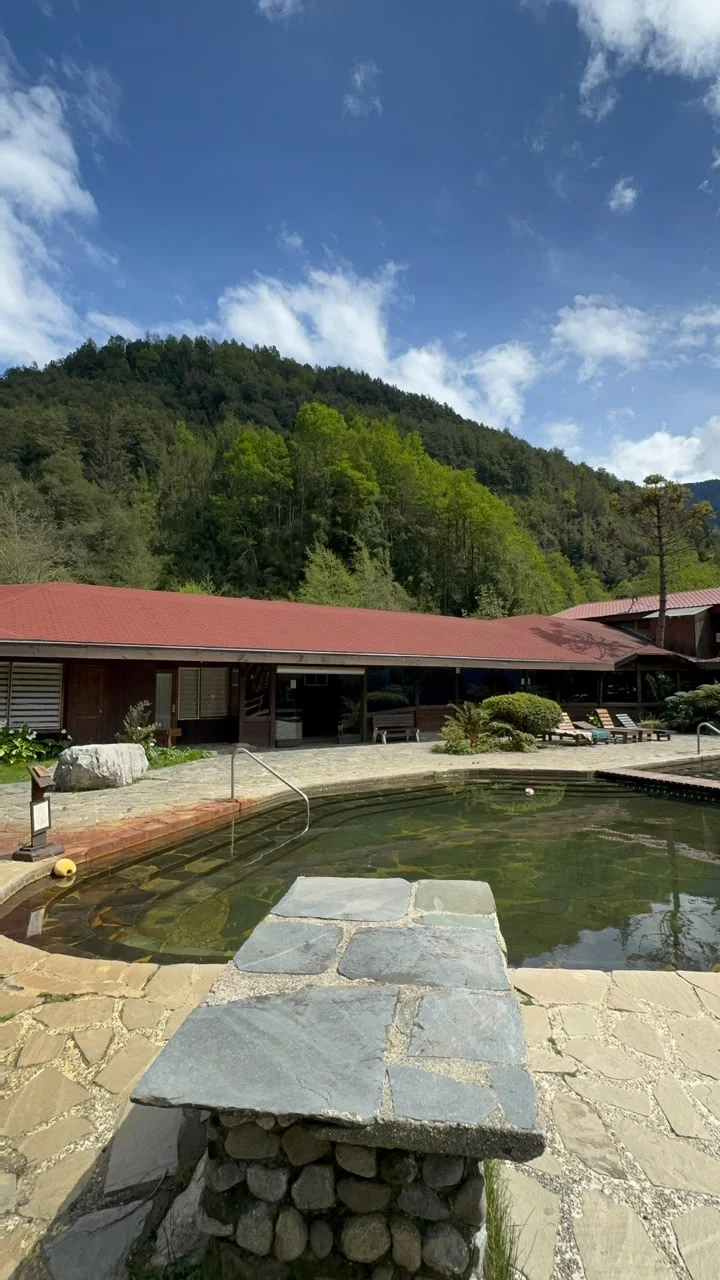 Piscina exterior frente a una construcción de madera en Termas Coñaripe