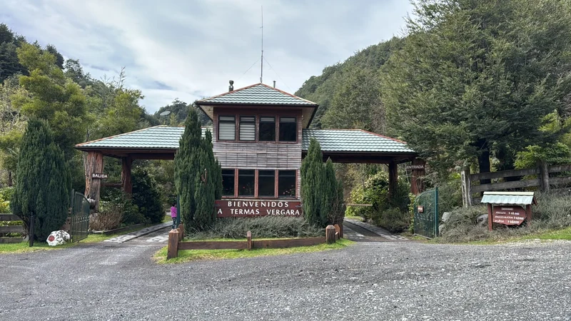 Acceso de madera y letrero de bienvenida de Termas Vergara entre árboles