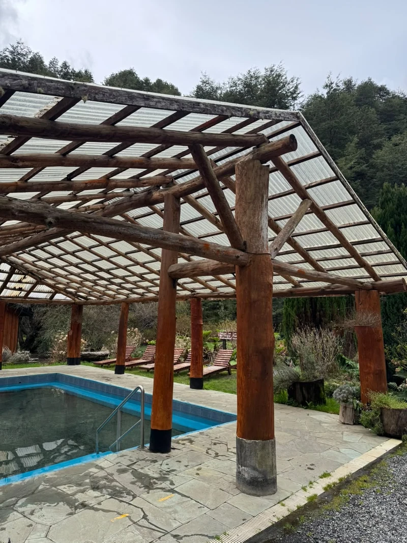 Piscina de Termas Vergara bajo una estructura de troncos, rodeada de vegetación
