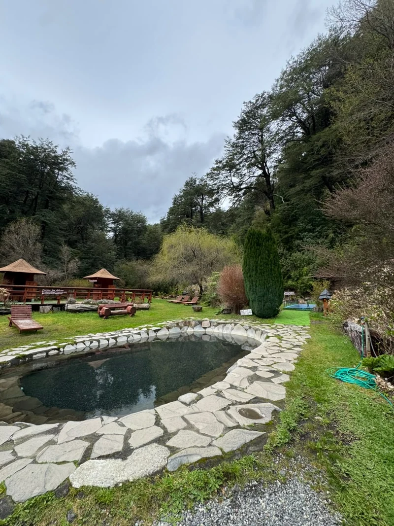 Piscina exterior circular de piedra junto a los jardines
