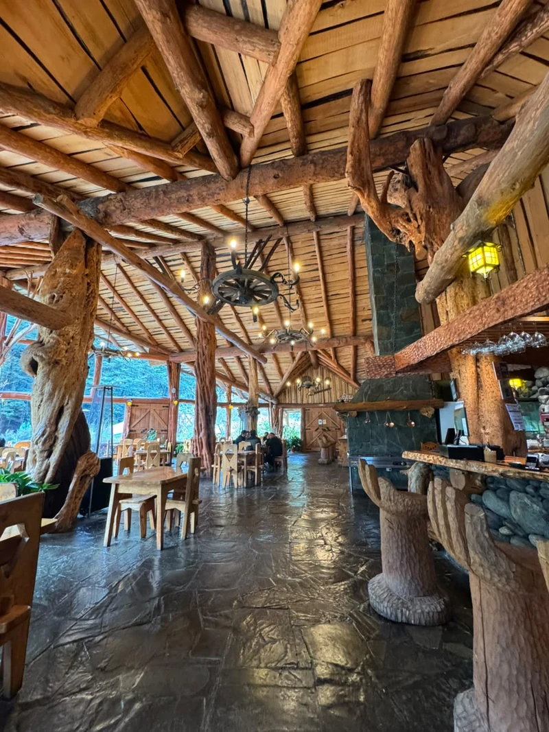 Interior de Los Mañihuales con mesas, madera y lámparas
